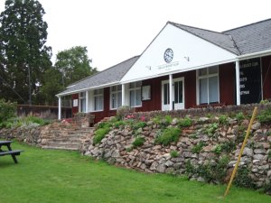 A single story long building with a verandah and central porch with clock.