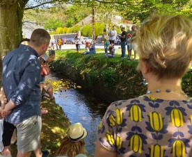 Residents and duck sponsors gather along the stream as the ducks race by (mostly)