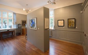 A light and spacious exhibition with central pillar, wooden floors and olive-coloured panelling