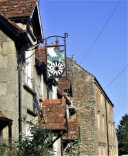 A stone cottage with beautiful hanging iron sign showing the Dinder Dragon