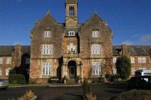 imposing double-gabled stone with stone porch between gables and a bell tower